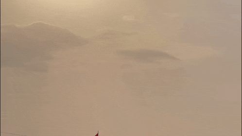 a flag is waving in the wind with the sun shining behind it