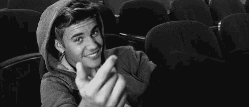 a black and white photo of a young man in a hoodie sitting in a theater .