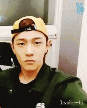 a young man wearing a yellow hat and a green jacket looks at the camera
