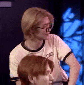 a man wearing glasses and a white shirt is standing next to another man with red hair .