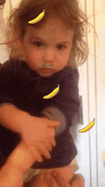 a little girl with bananas on her face looks angry