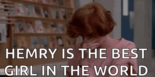 a woman in a pink shirt is sitting in front of a bookshelf and says hemry is the best girl in the world .