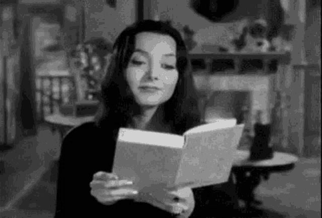 a woman is reading a book in a black and white photo .
