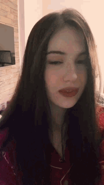 a close up of a woman 's face with her eyes closed and red lipstick on her lips .