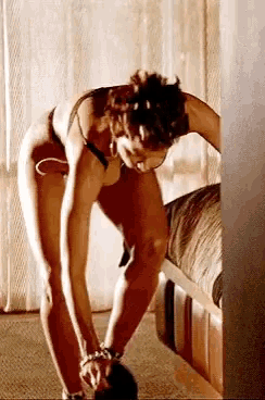 a woman in lingerie is bending over in a bedroom .