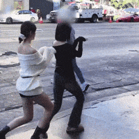 a woman in a white off the shoulder sweater is running across a street