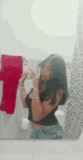 a woman is taking a selfie in front of a mirror in a bathroom .