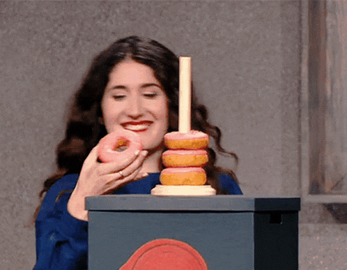 a woman eating a donut next to a stack of donuts on a stick