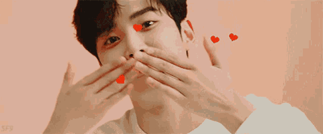 a young man with red hearts on his face .