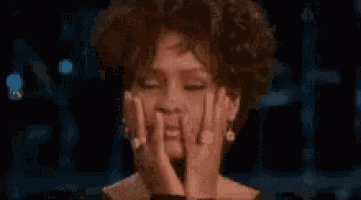 a woman is covering her face with her hands while wearing earrings and a ring .