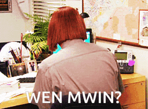 a woman sits at a desk with the words wen mwin written on the back of her shirt
