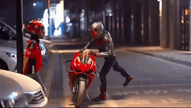 a man is pushing a red motorcycle down the street
