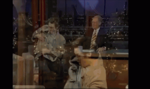 a man in a suit sits at a table with a man in a chair