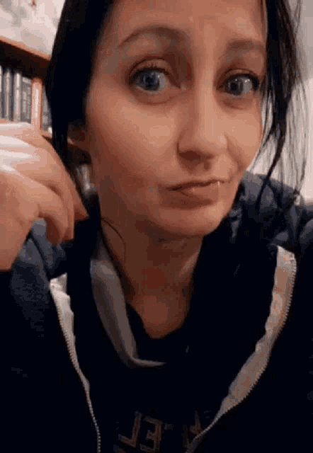 a woman with a piercing in her lip is making a funny face while looking at the camera .