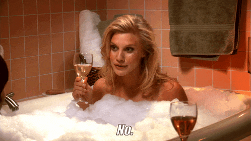 a woman in a bathtub holds a glass of wine and says " no "