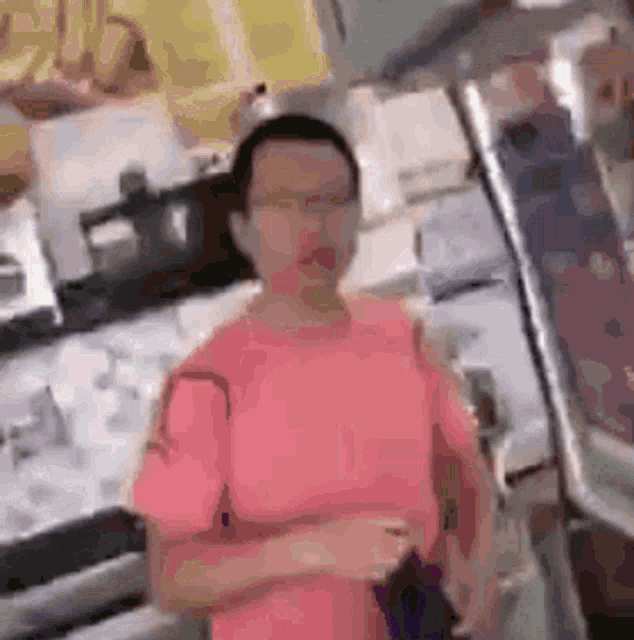 a man in a pink shirt is standing in a store .