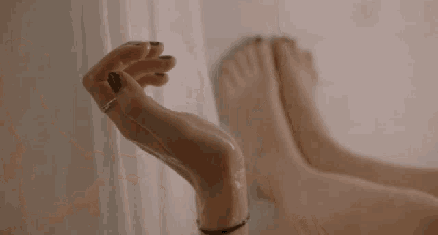 a woman is laying in a bathtub with her feet up and looking at her reflection in the mirror .