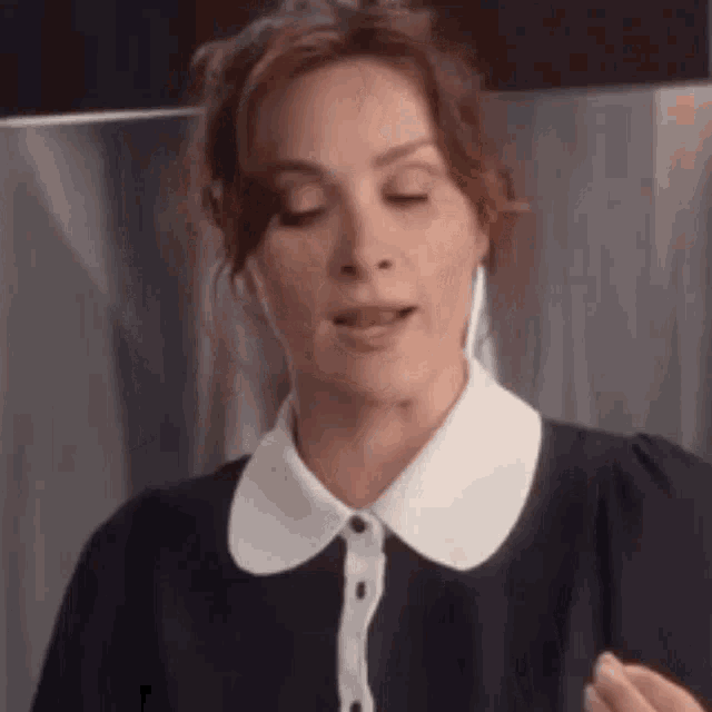 a woman wearing a black dress with a white collar and ear buds .