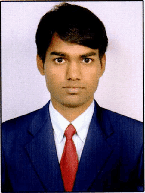 a man wearing a blue suit and red tie looks at the camera