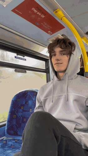 a man sitting on a bus with a sign that says they are ok above him