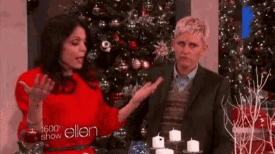 a man and a woman are sitting in front of a christmas tree .