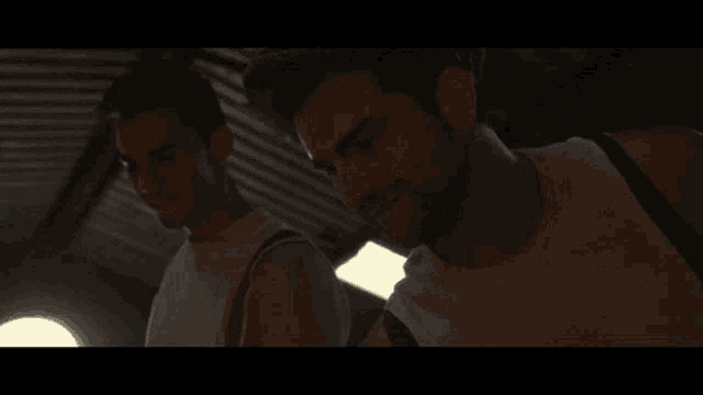 two men are standing next to each other in a dark room and one of them is smiling