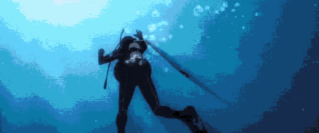 a scuba diver is swimming in the ocean holding a spear .