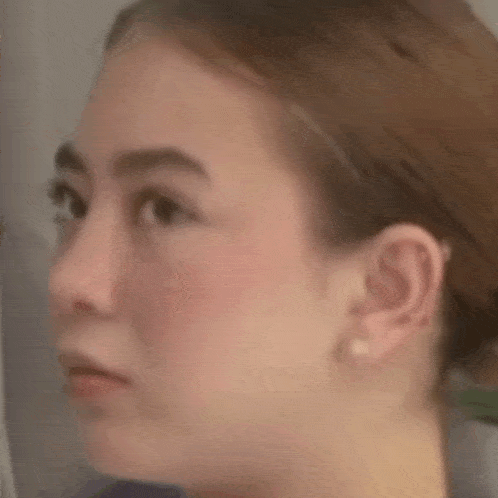 a close up of a woman 's face with a serious look on her face and earrings .