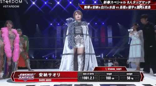 a woman in a white cape stands on a stage in front of a stardom advertisement