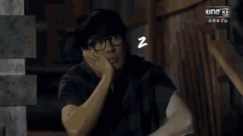 a man wearing glasses is sleeping with a zzz symbol above his head