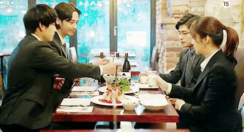 a group of people are sitting at a table with plates of food and a sign that says 15