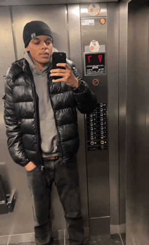 a man taking a picture of himself in an elevator with a sticker on the wall that says ' elevator ' on it