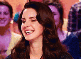 a woman with long dark hair is smiling in front of a crowd of people .