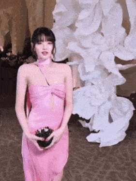 a woman in a pink dress is standing in front of a display of flowers .