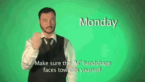 a man in a suit and tie is making a sign that says monday make sure the m handshape faces towards yourself