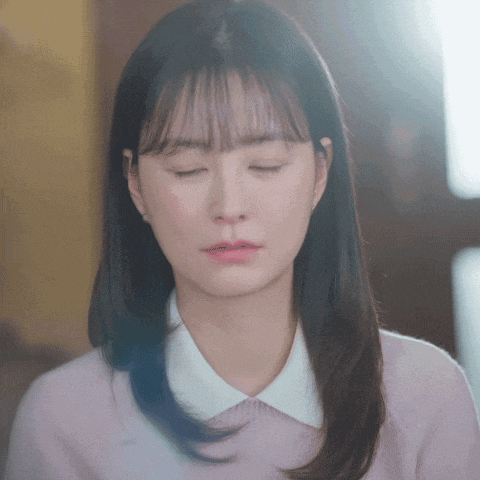 a woman with her eyes closed wearing a pink shirt