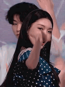 a woman in a blue polka dot dress is dancing with a man