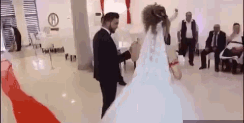 a bride and groom are dancing in a room while a group of people watch .