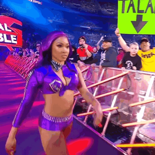 a woman in a purple outfit is walking in front of a sign that says " tala "