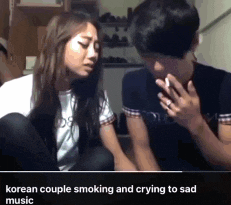 a man is smoking a cigarette next to a woman who is crying to sad music