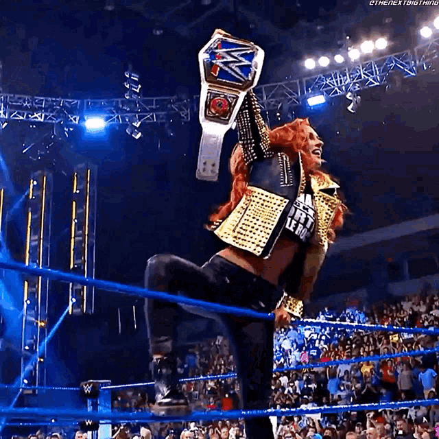 a woman in a wrestling ring is holding a championship belt .