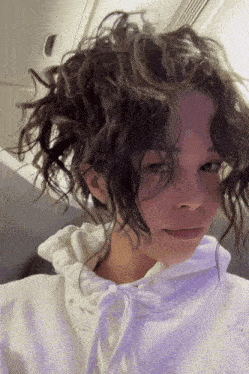 a woman with curly hair is wearing a white sweatshirt