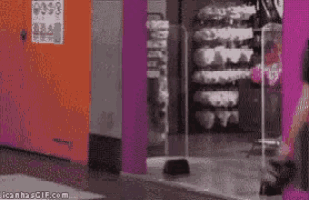 a woman is walking through a store with a sign that says iconhasgif.com on it