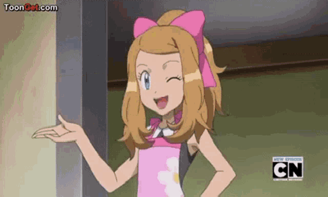 a girl in a pink dress with a pink bow on her head is standing next to a wall .