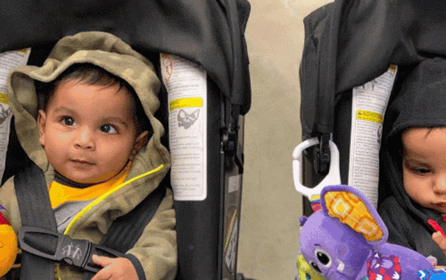 two babies are sitting in car seats and one has a toy attached to it