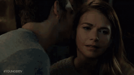 a man is kissing a woman on the forehead in a bar .