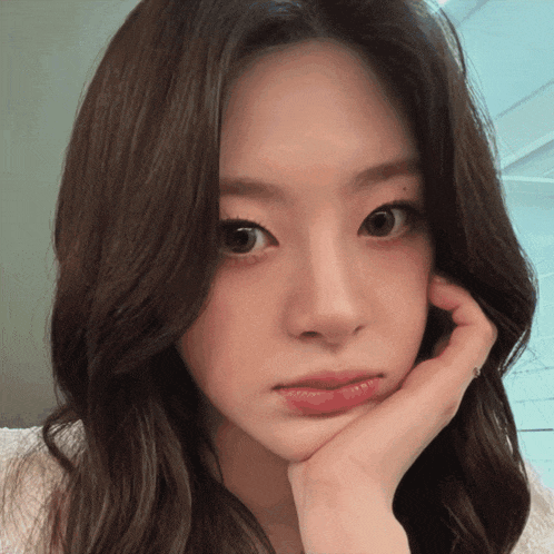 a woman with her hand on her face looks at the camera