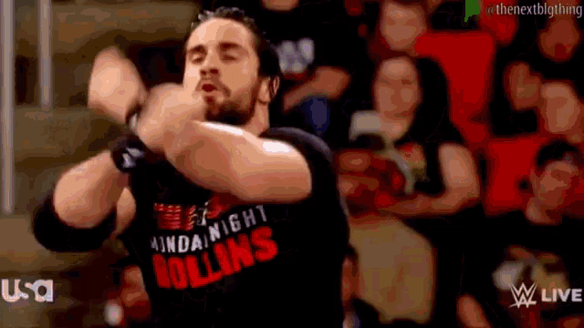 a wrestler is wearing a black shirt that says monday night rollins and is dancing in front of a crowd .