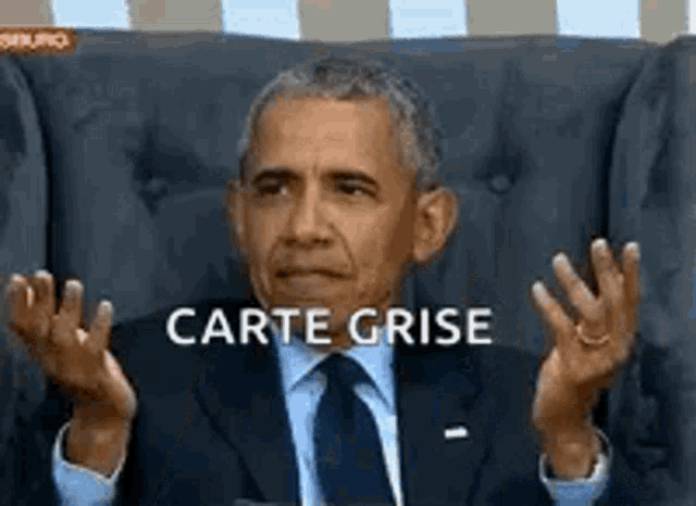 a man in a suit and tie is sitting in a chair with his hands in the air .