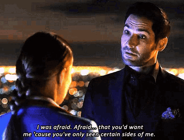 a man in a suit talks to a woman in a blue shirt